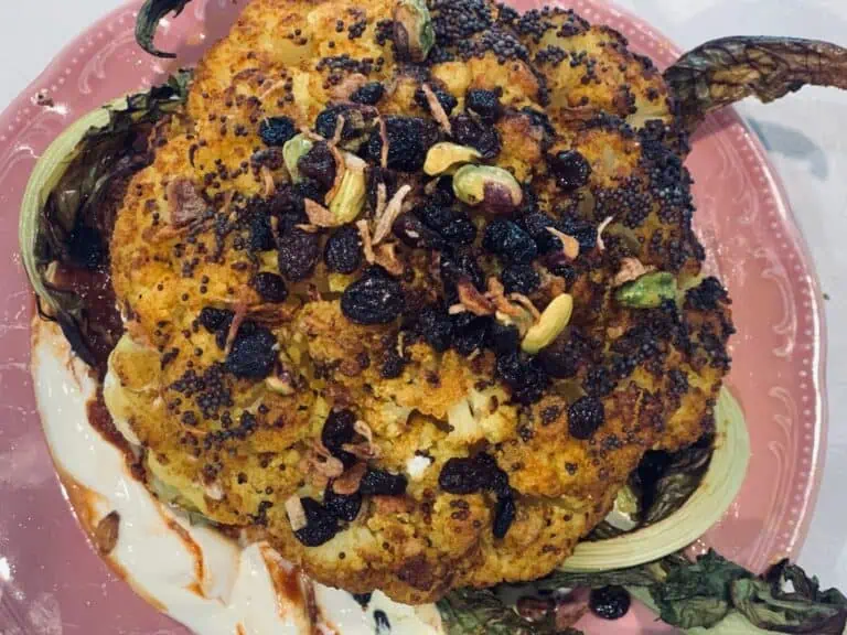 Golden roasted cauliflower with pepper berries and pistachios, served on a pink plate at Fleurieu Food & Wine.