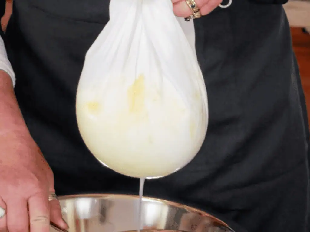 Draining whey from the curd in an Adelaide cheesemaking class