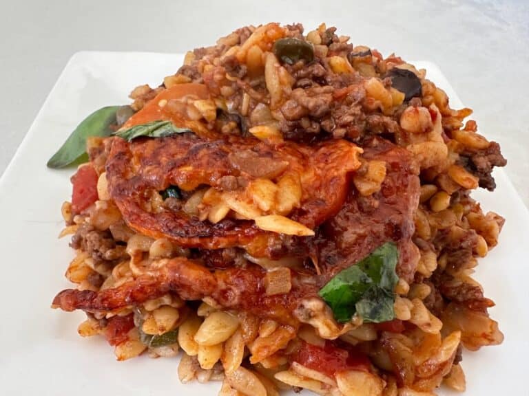 Succulent serving of traditional beef lasagna with rice, tomato sauce, and fresh basil garnished.