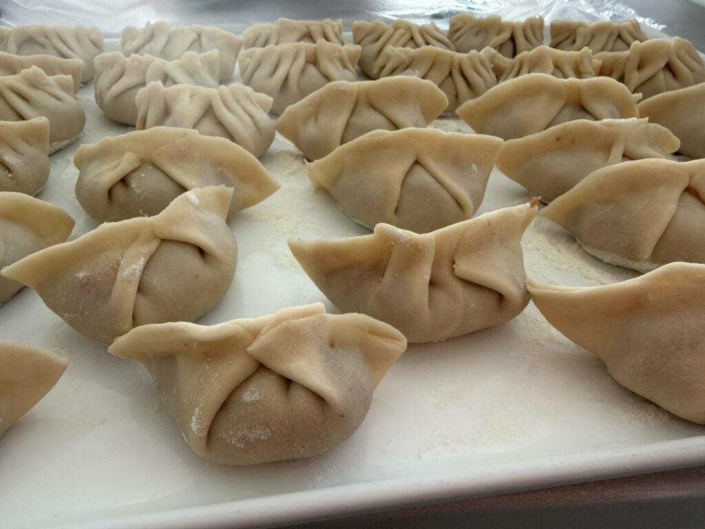 Steamed dumplings on a black plate drizzled with dark soy at a Fleurieu Food and Wine dumpling class