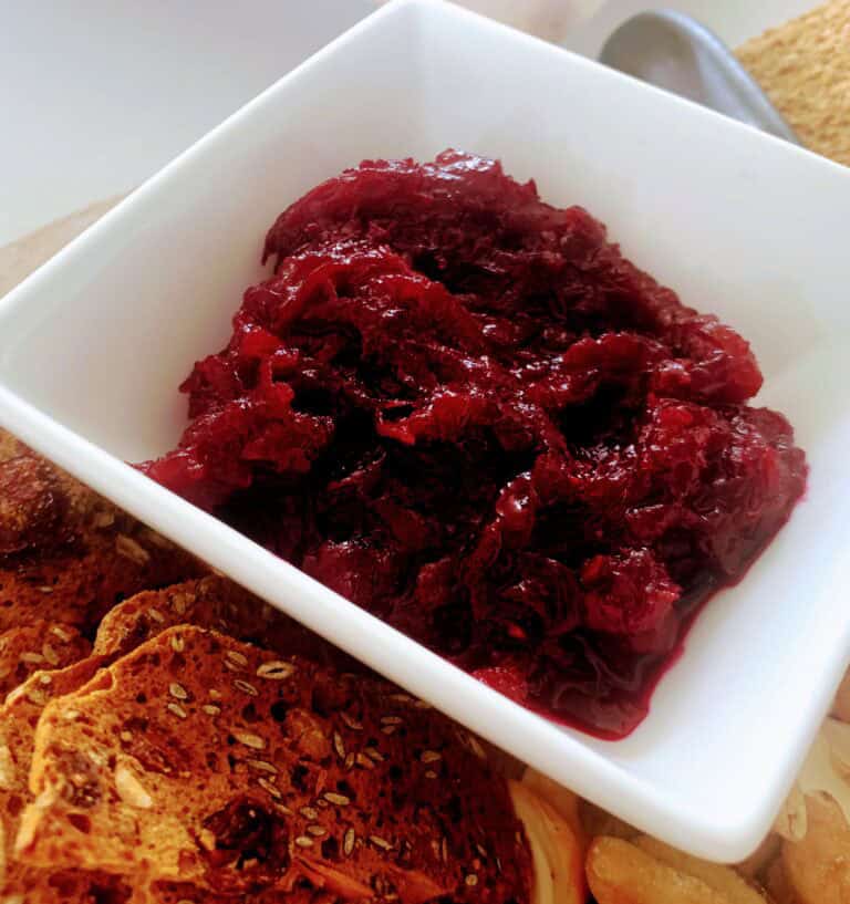 Homemade berry jam in a white bowl on a wooden table.