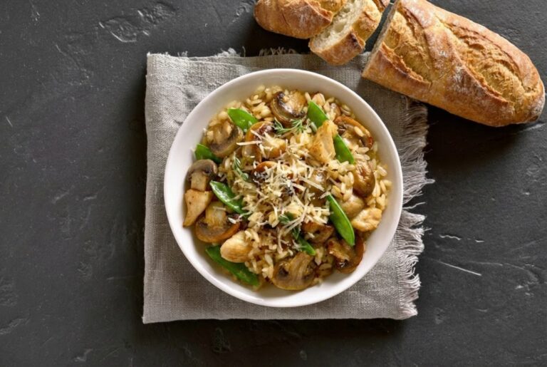 Baked chicken mushroom risotto with leek and thyme served in a white bowl on dark slate