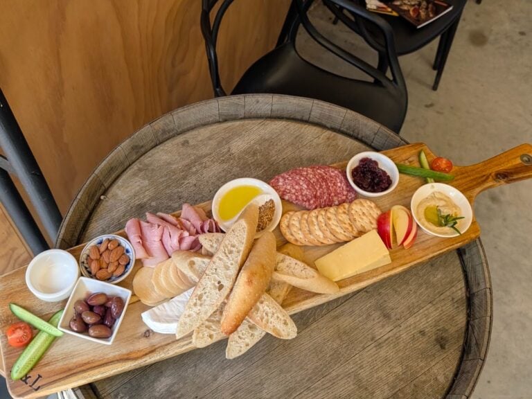 A grazing board of cheese, cured meats, bread and olives on a wine barrel in McLaren Vale