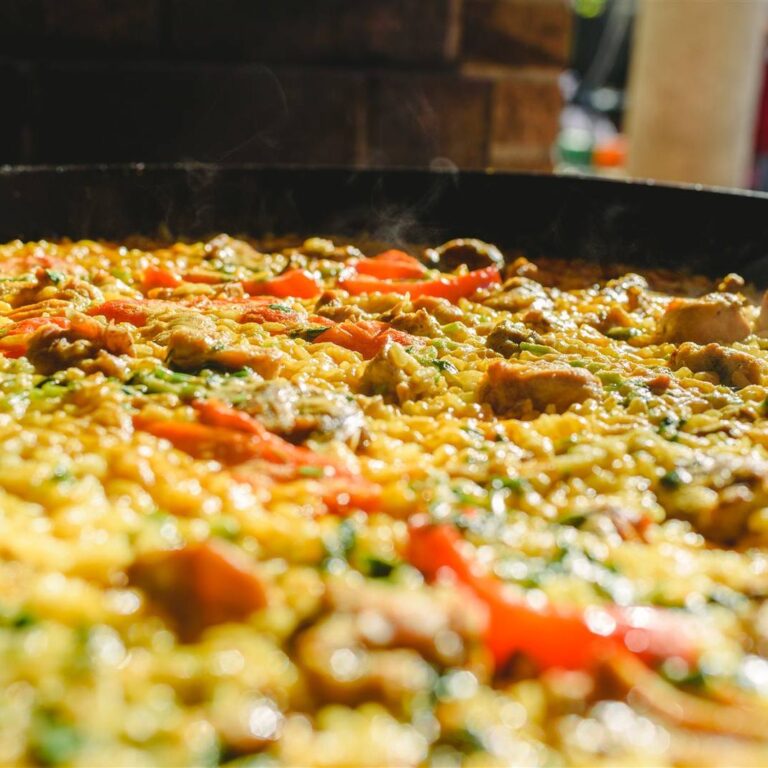 Chicken paella with peppers and saffron rice in a wide pan