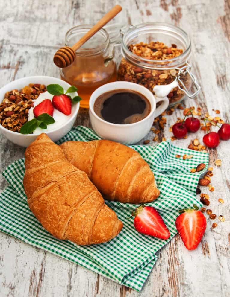 Freshly baked croissants with strawberries, granola, honey, and coffee, showcasing Fleurieu Food & Wine.