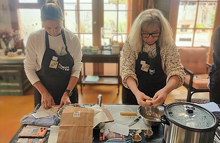 Two guests in Fleurieu Food and Wine aprons shaping potato gnocchi dough at the bench during a hands-on cooking class at Lot 50, Yankalilla