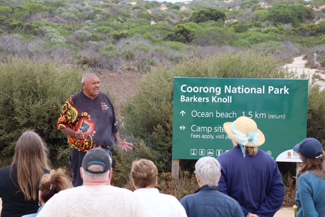 Ngarrindjeri Elder Mark Koolmatrie speaking to a group of visitors beside the Barkers Knoll sign in Coorong National Park