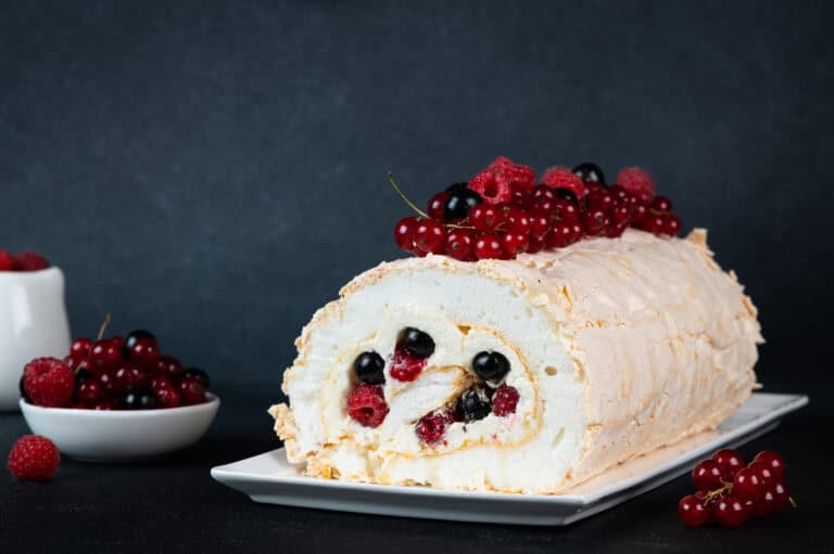 Sweet berry Swiss roll with fresh red and black currants on top, perfect for food and wine pairing.