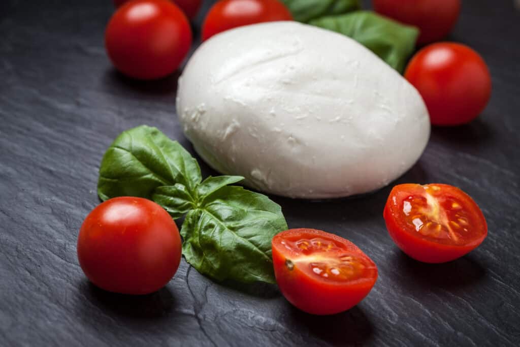 Fresh mozzarella cheese with cherry tomatoes and basil leaves.