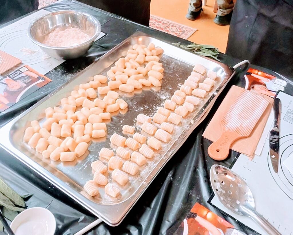 A tray of freshly rolled potato gnocchi, ridged by hand on a wooden gnocchi board and dusted with flour, beside fresh sage at a Fleurieu Food and Wine gnocchi cooking class