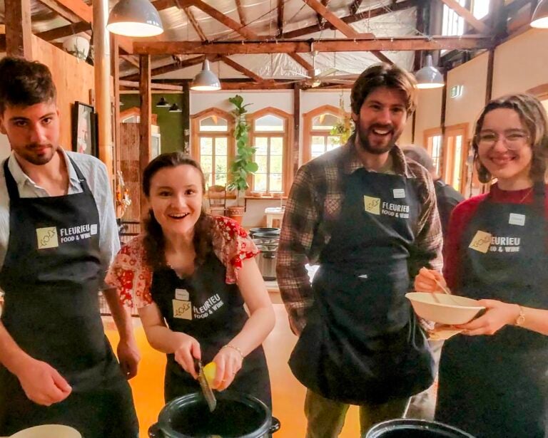 Four guests in Fleurieu Food and Wine aprons laughing together as they cook their gnocchi in pots at a class at Lot 50 on the Fleurieu Peninsula