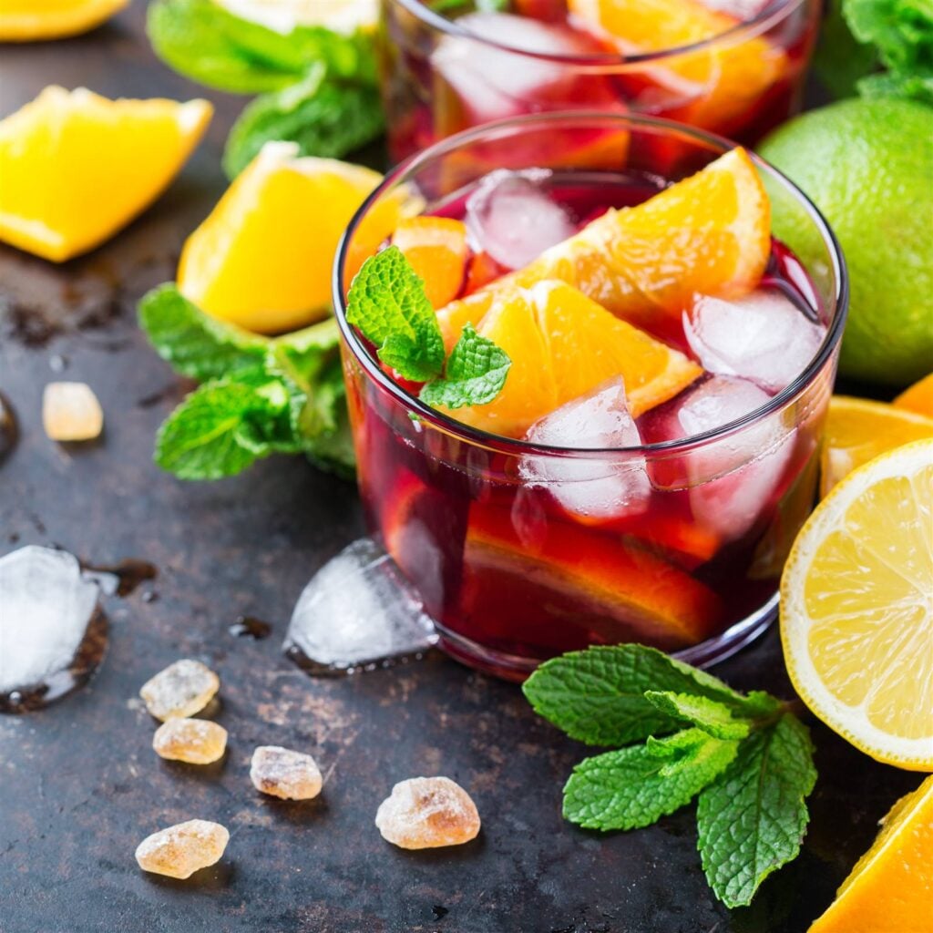 Glasses of red sangria with orange slices, ice and fresh mint